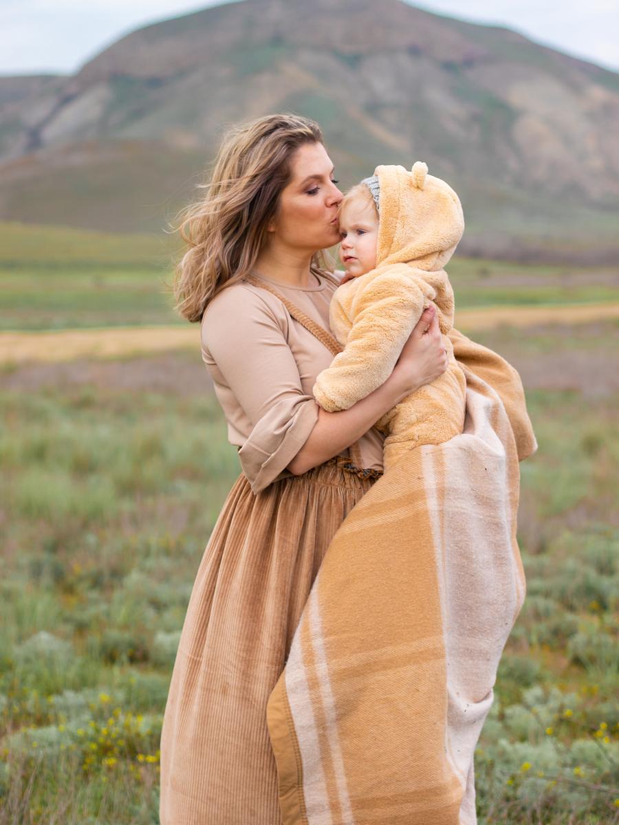A mother holding and kissing her child in a mountain landscape