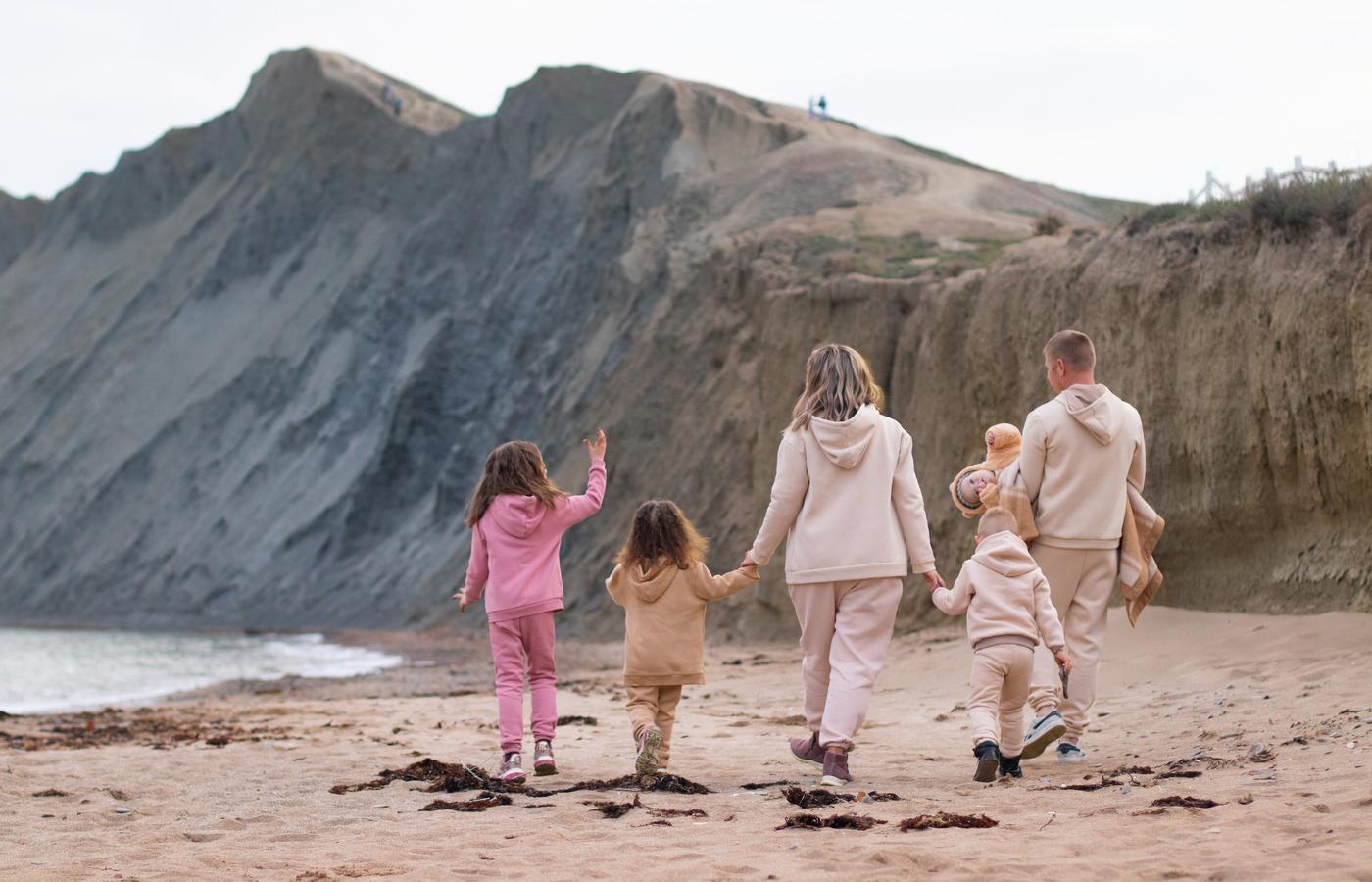 A family walking hand in hand along a mountain coastline