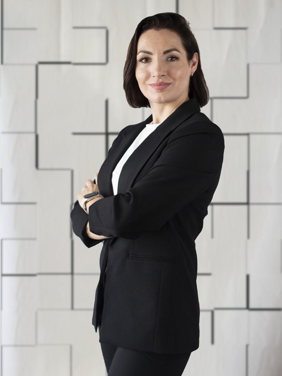 Professional woman standing with folded arms in a black blazer