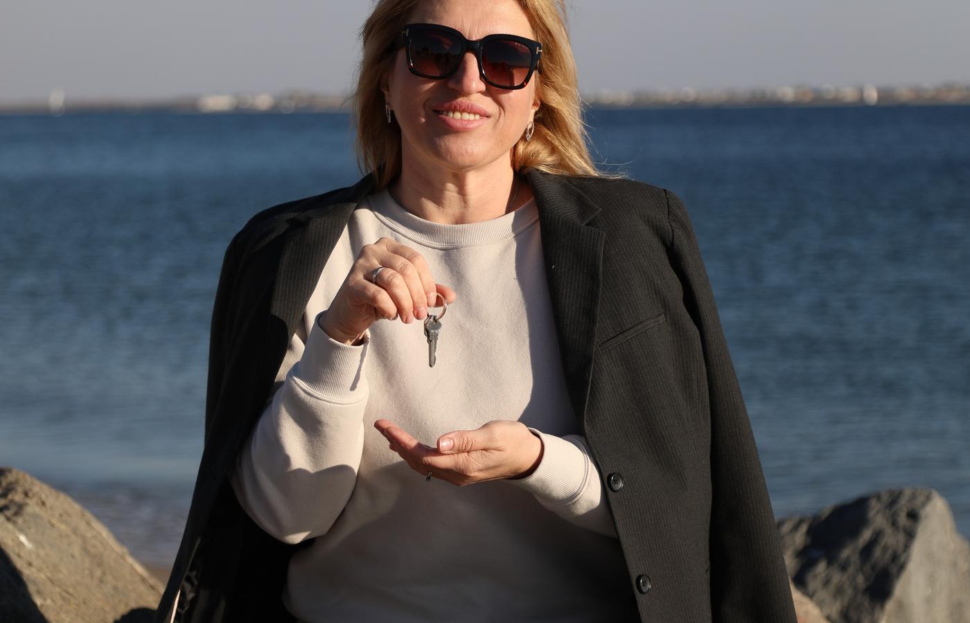 Woman holding keys while seated by the water in New York