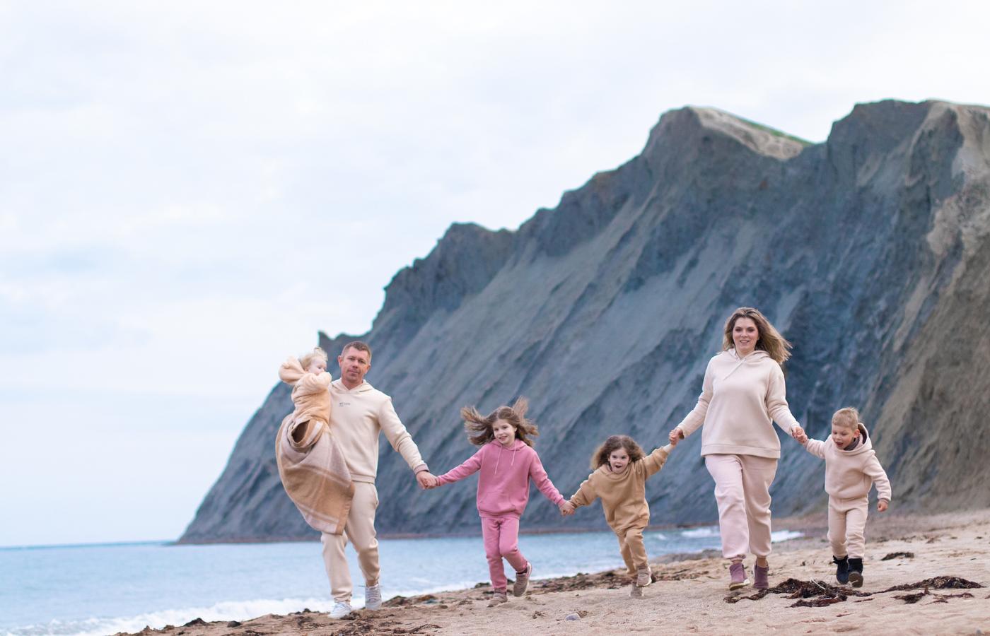 A family running hand in hand toward the camera on a beach