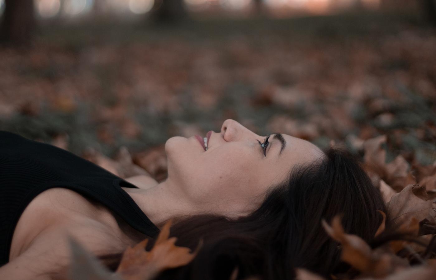 A woman lying among autumn leaves in quiet profile