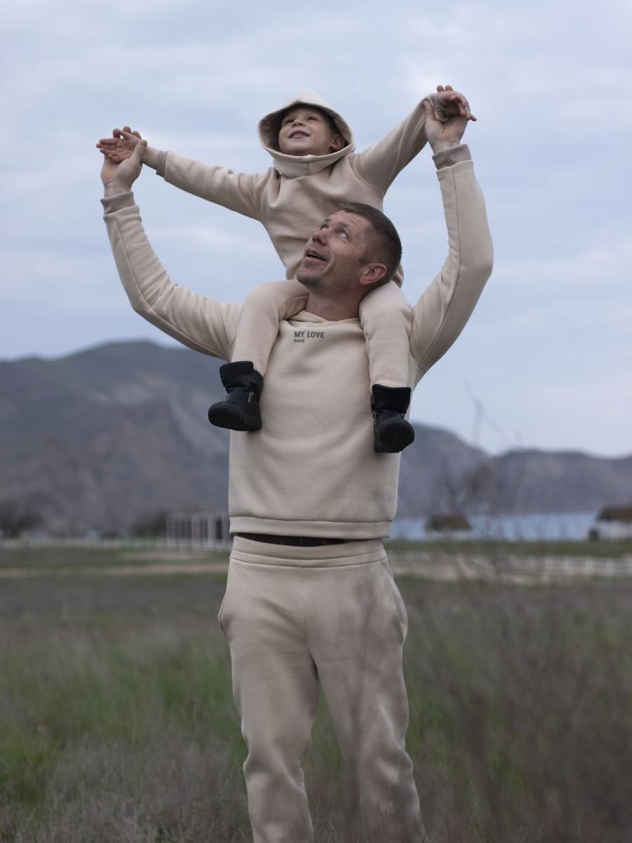 A smiling father carrying his son on his shoulders outdoors