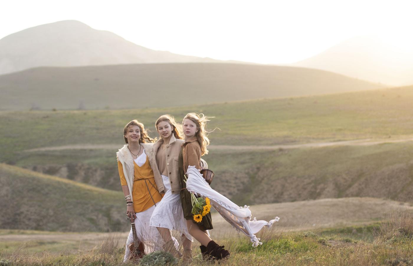 Three women walking together through a sunlit mountain valley