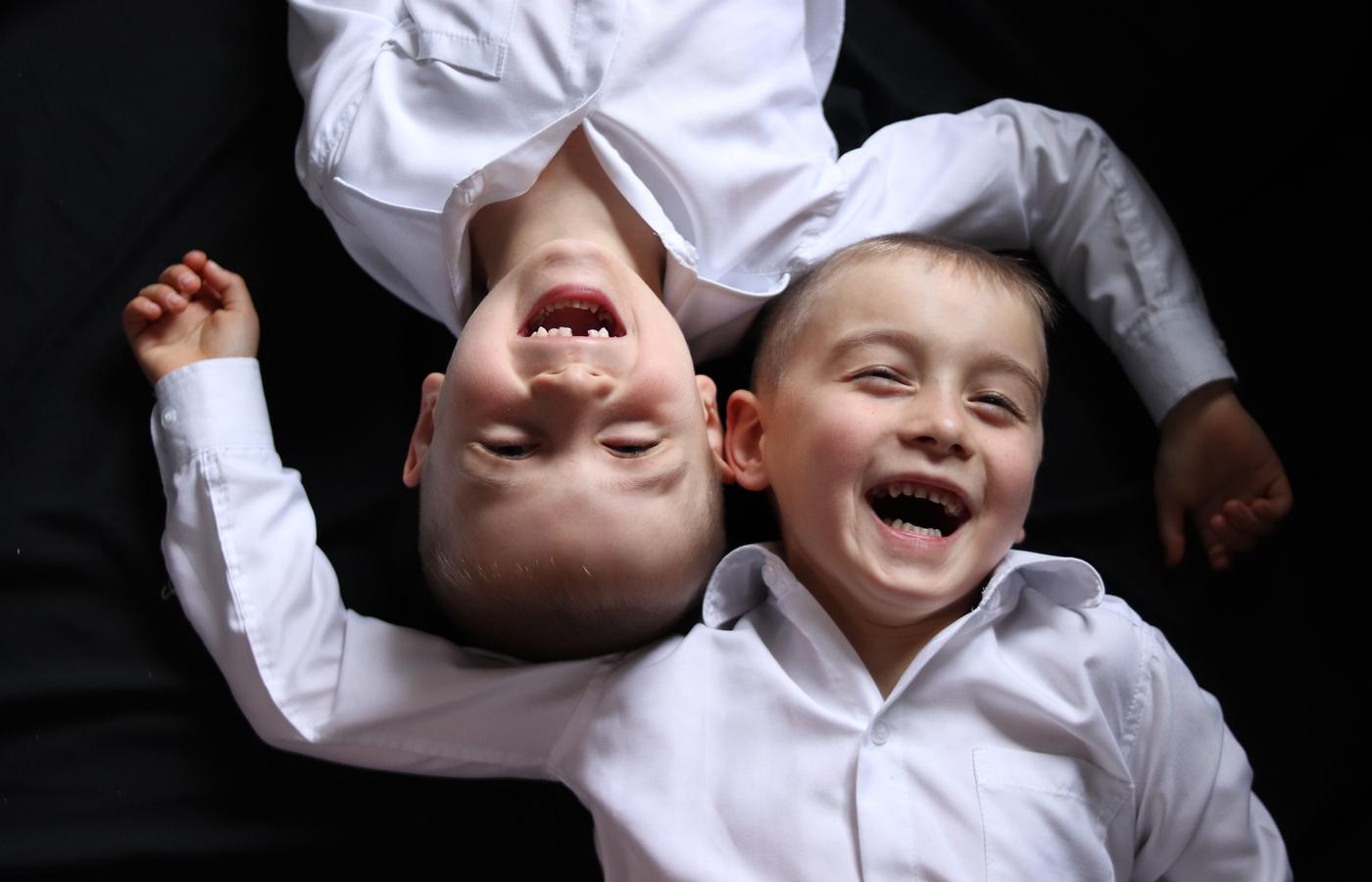 Two brothers laughing together while one hangs upside down