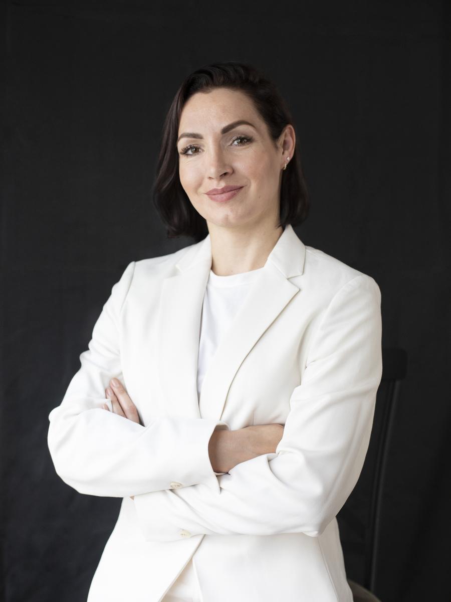 Professional woman in a white suit against a dark studio background