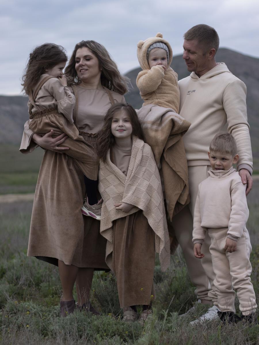 A family standing close together in softly coordinated neutral clothing