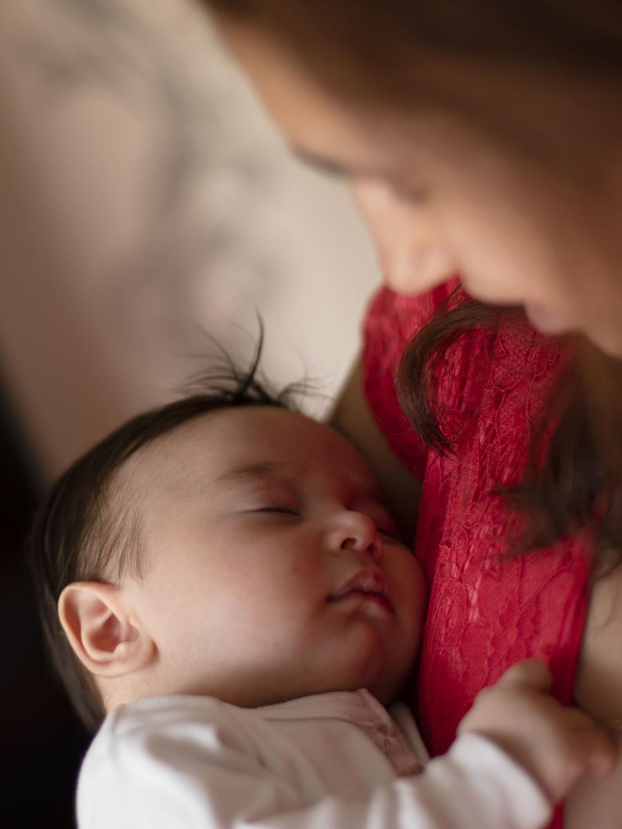 A sleeping newborn resting close against their mother