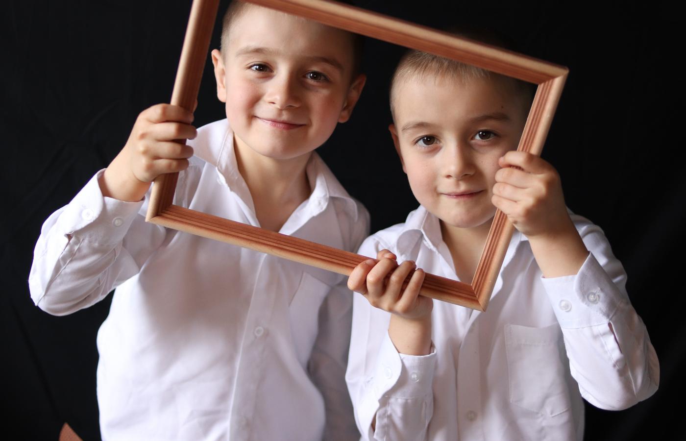 Two brothers smiling together inside a wooden picture frame