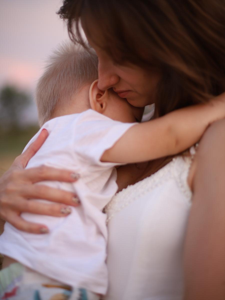 A child resting against their mother's shoulder in a close embrace