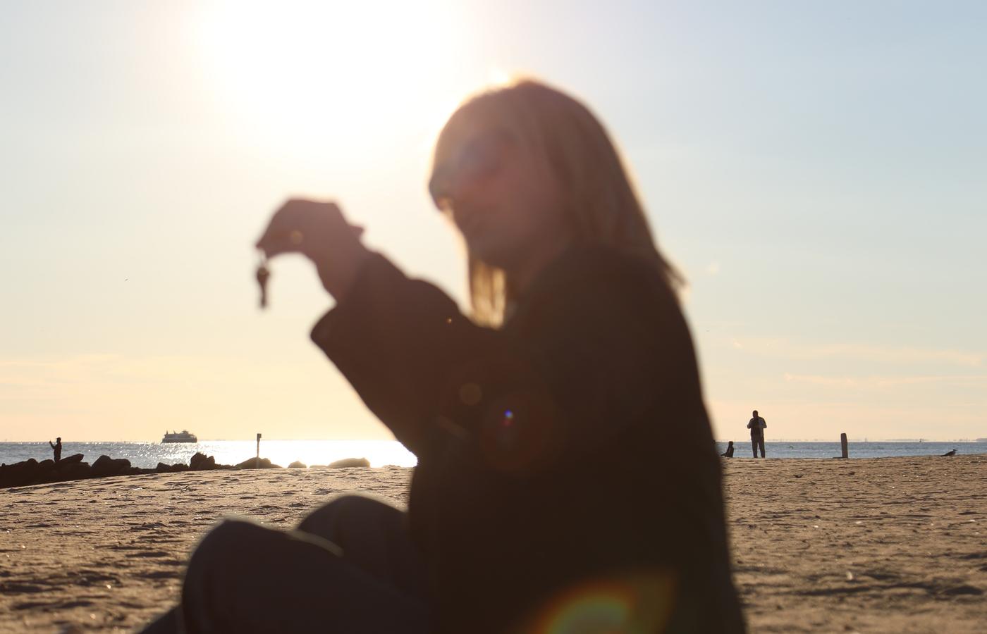 Silhouetted woman holding keys against a bright Atlantic sunset