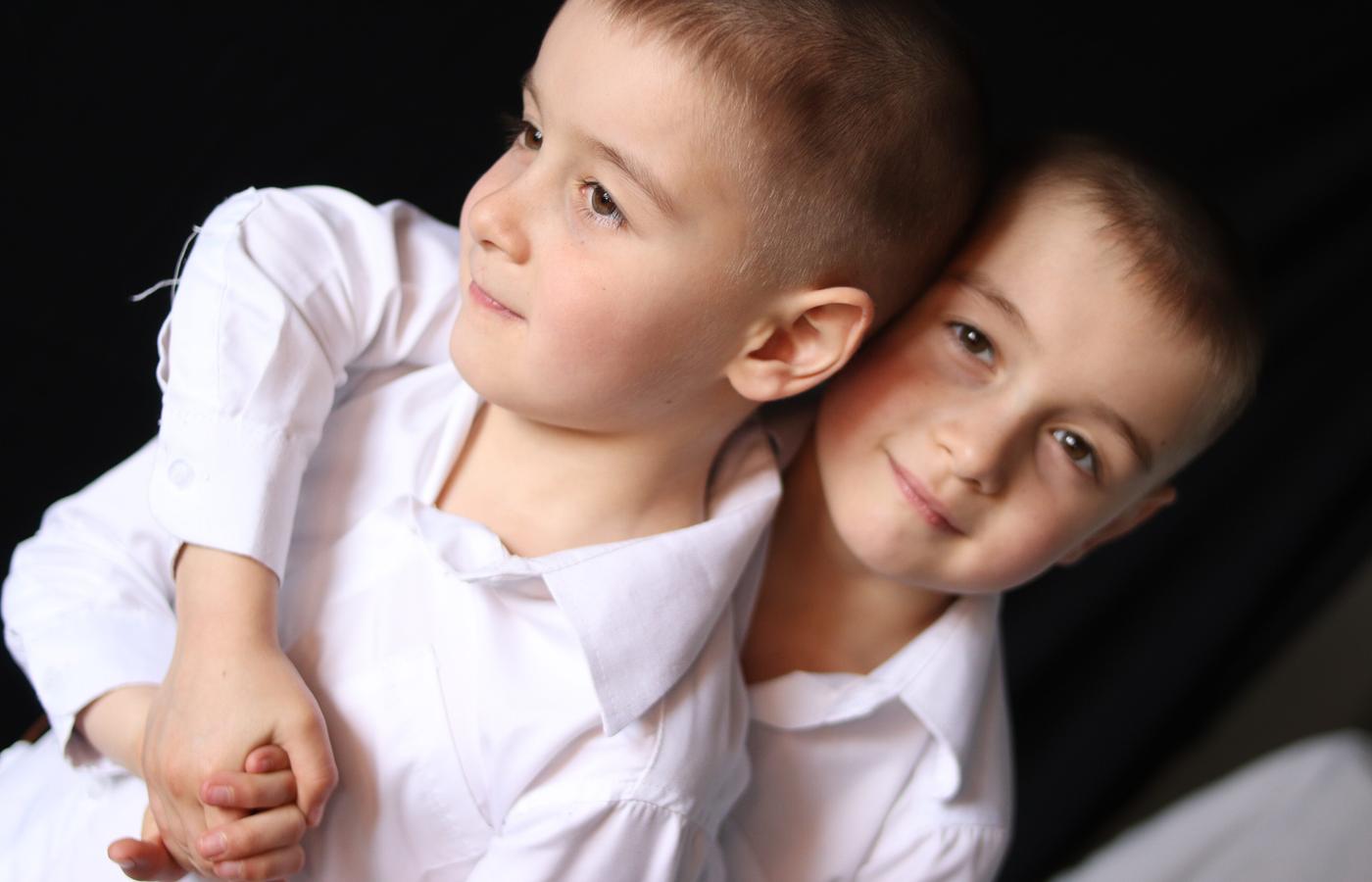 Two brothers standing arm in arm for a playful studio portrait