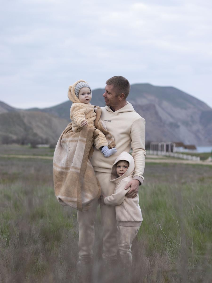 A father holding his two sons close in an outdoor family portrait